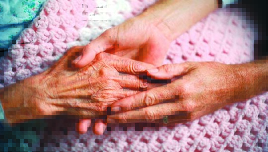 Home health aid holding hands with an elderly woman